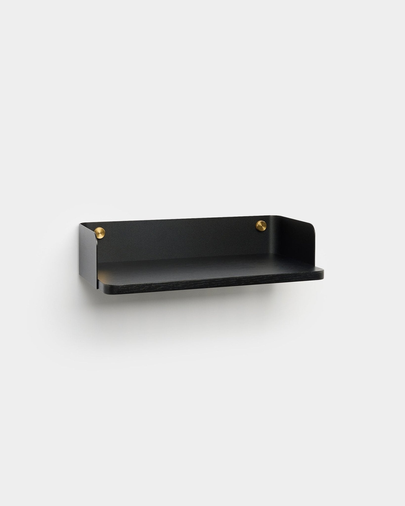 La libreria Linn di WoodUpp, con finitura minimalista black e viti di montaggio brass, è montata su una parete grigio chiaro e completa un interior design nordico.